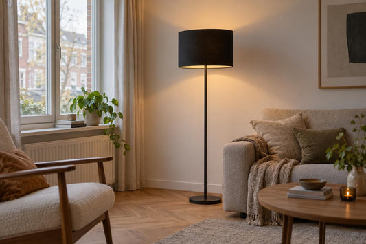 Zwarte cilindervormige lampenkap op een vloerlamp in een woonkamer